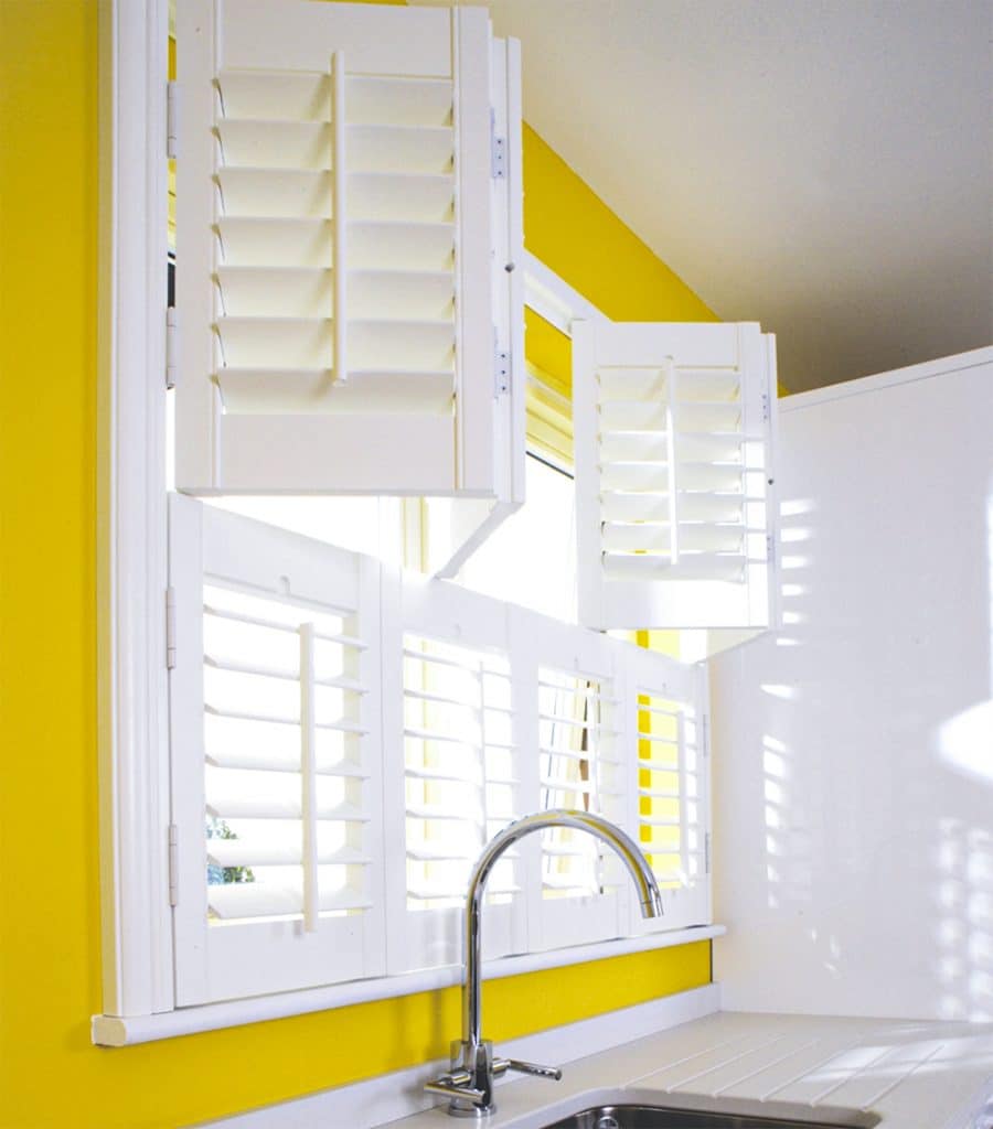 Tier on tier wooden shutters in yellow kitchen
